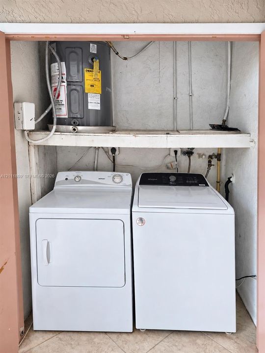 Dedicated laundry closet featuring a side-by-side washer and dryer, built-in overhead shelving, and an integrated water heater