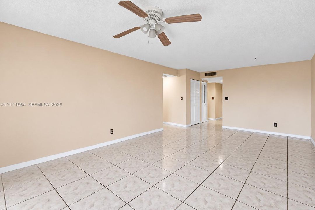 Open interior space featuring neutral wall tones, large-format tile flooring, and a ceiling fan with integrated lighting