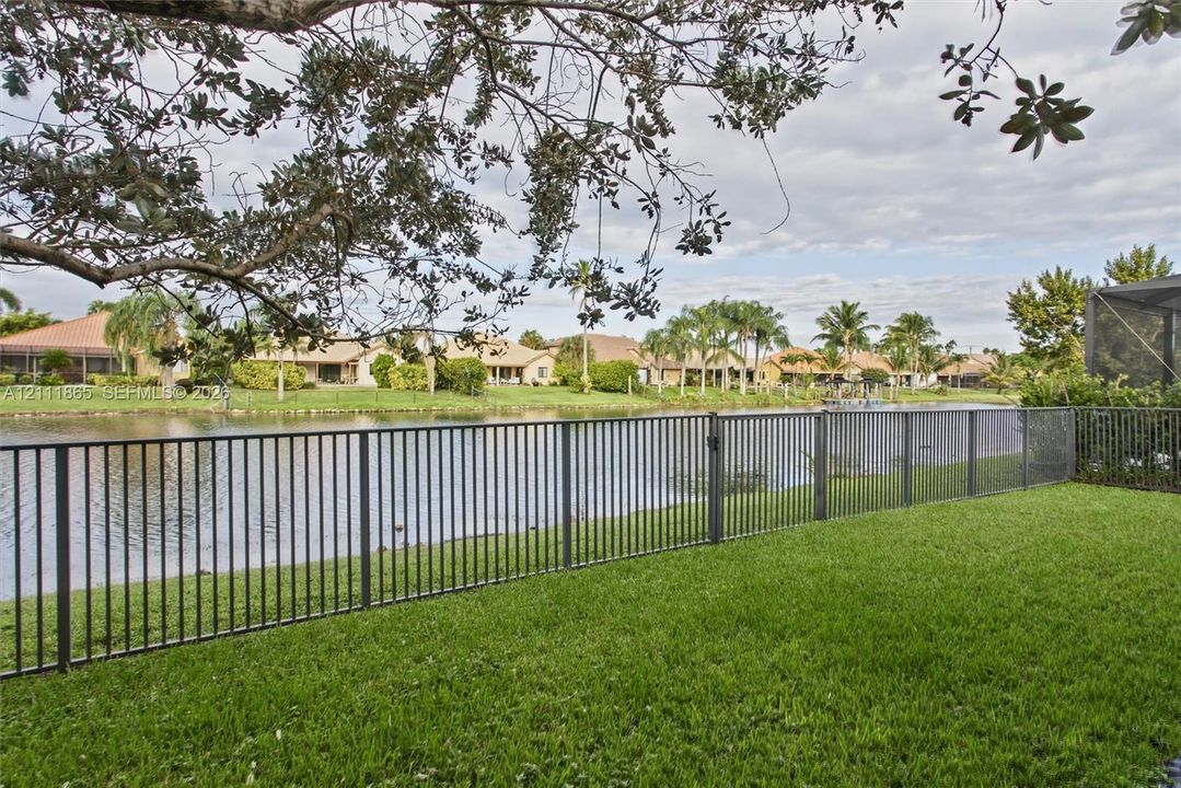 Fenced backyard featuring a manicured lawn and direct water frontage