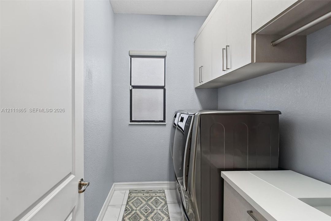 Spacious Laundry featuring custom cabinetry, a solid-surface countertop with built-in hanging rod.