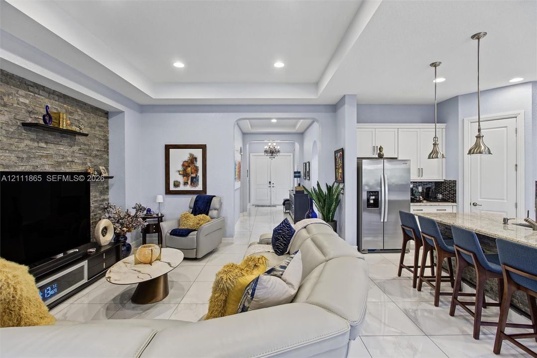 Living space featuring a stone accent wall & recessed tray ceiling.