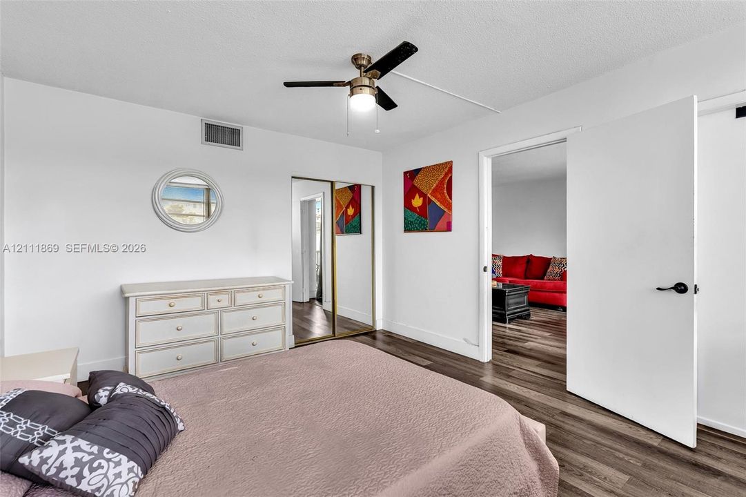Wood-finish flooring, ceiling fan with integrated light, and sliding mirrored closet doors