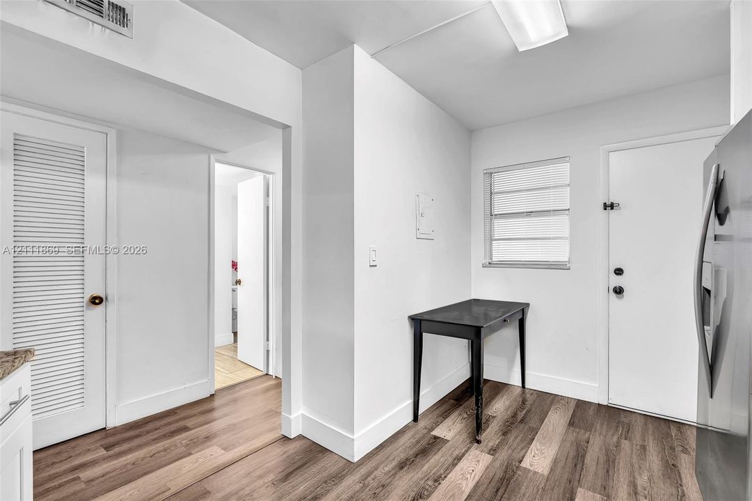 Interior space featuring wood-finish flooring, a horizontal louvered closet door, a flush-mount ceiling light fixture, and a window with horizontal blinds