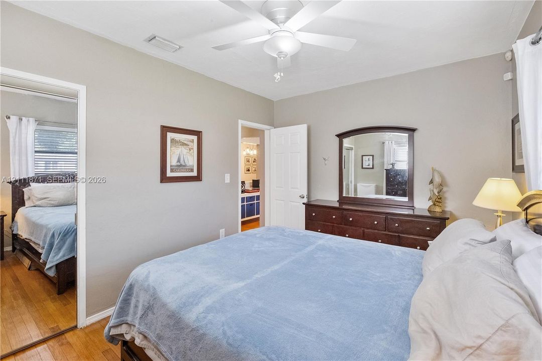 Room featuring wood-finish flooring, a white ceiling fan with integrated lighting, and a multi-panel interior door