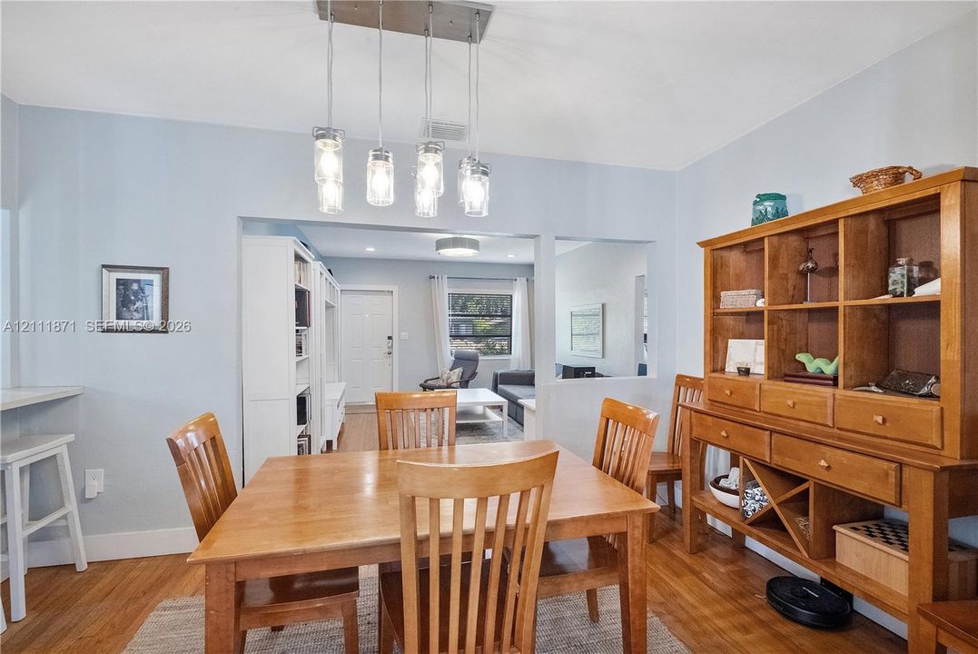 Dining area featuring wood-finish flooring, a multi-pendant glass fixture, and built-in cabinetry