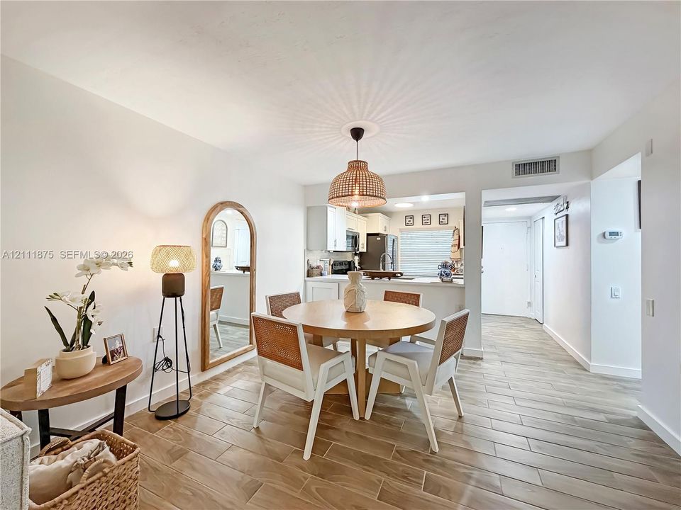 Dining area featuring wood-finish flooring, a woven pendant light fixture, and an arched wall-mounted mirror