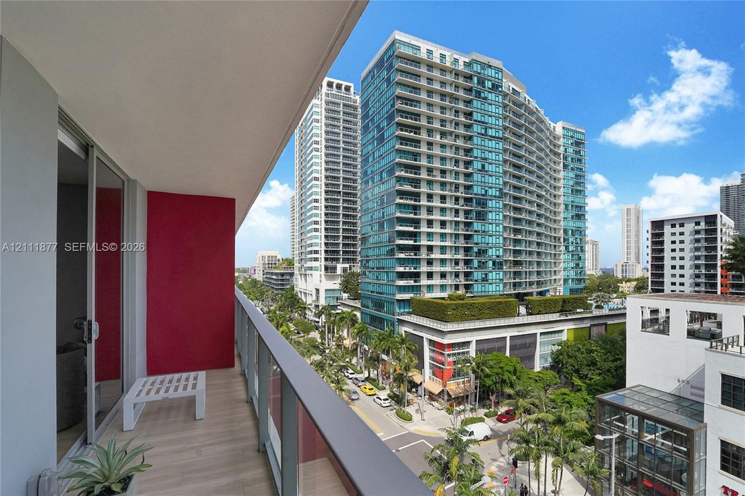 Covered balcony featuring wood-finish flooring, glass panel railing, and sliding glass door entry