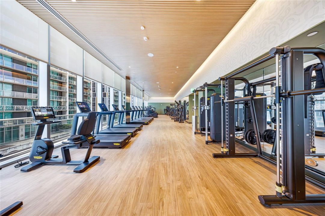 Fitness center featuring wood-finish flooring, slatted wood-paneled ceilings, floor-to-ceiling windows, and recessed lighting