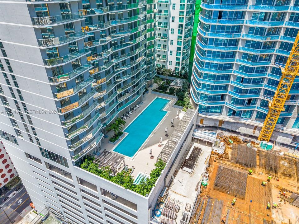 High-rise swimming pool terrace featuring a lap pool, integrated spa, paved sun deck, and wood-slatted pergola