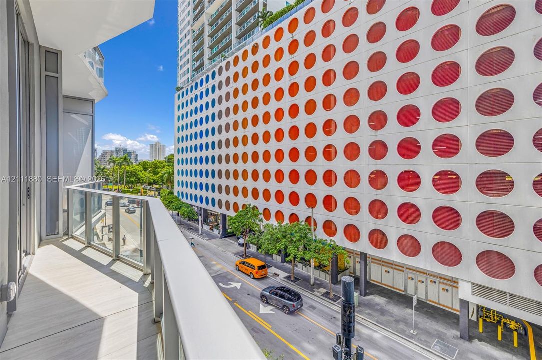 Private balcony with a glass and metal railing, tile flooring, and urban surroundings