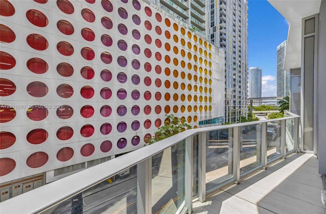 Covered balcony featuring glass paneled railings and light-toned tile flooring
