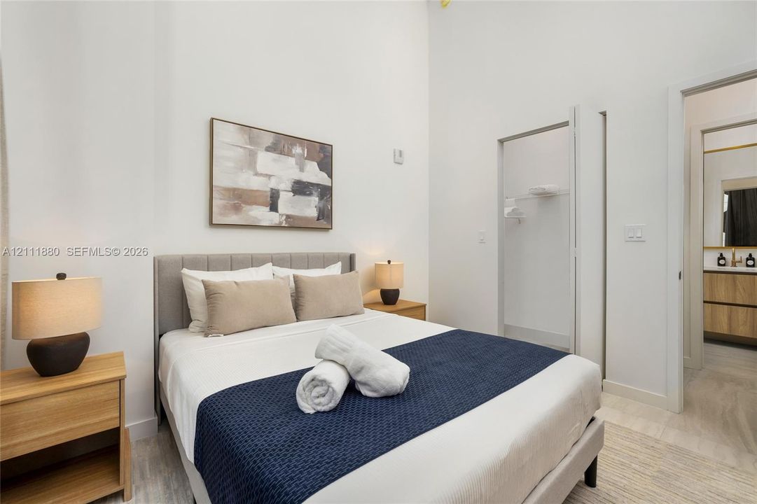 High ceilings, neutral wall palette, and light-toned flooring featuring a built-in closet with integrated shelving