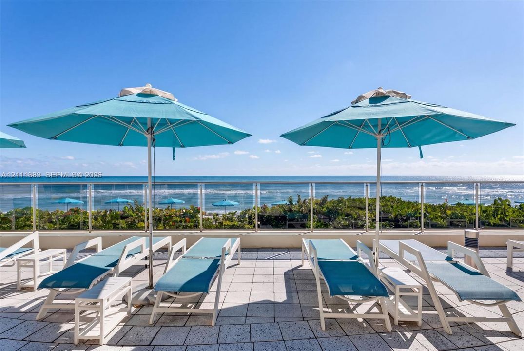 Outdoor terrace featuring stone tile flooring and a glass panel railing