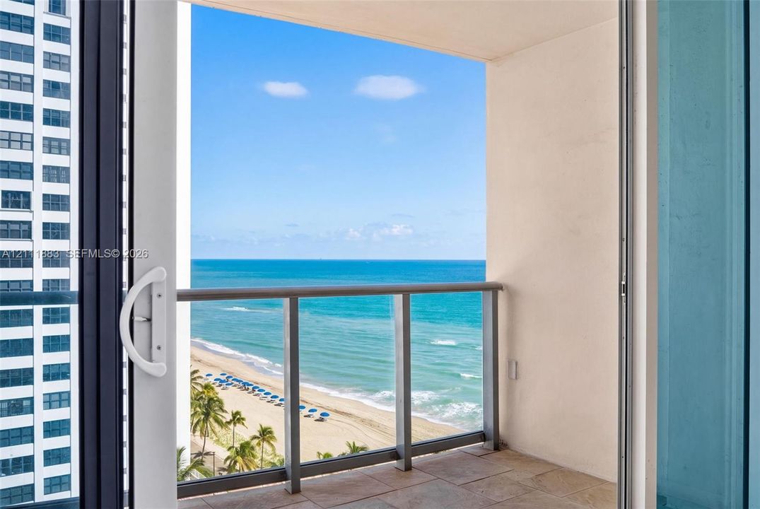Covered balcony featuring tile flooring and a metal-framed railing, showcasing direct oceanfront scenery