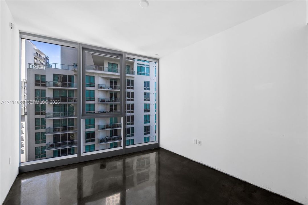 Floor-to-ceiling windows with dark framing, polished concrete flooring, and neutral white walls