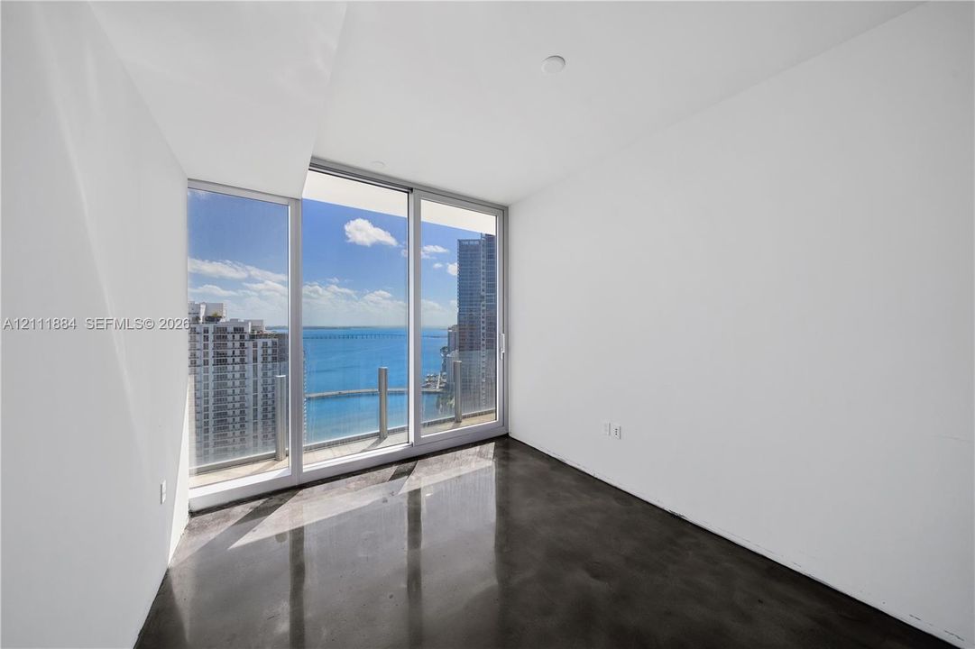 Floor-to-ceiling windows, polished concrete flooring, and water-fronting balcony access