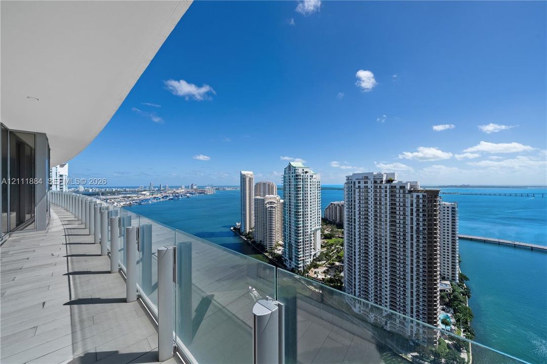Expansive wrap-around balcony featuring large-format tile flooring and frameless glass railings