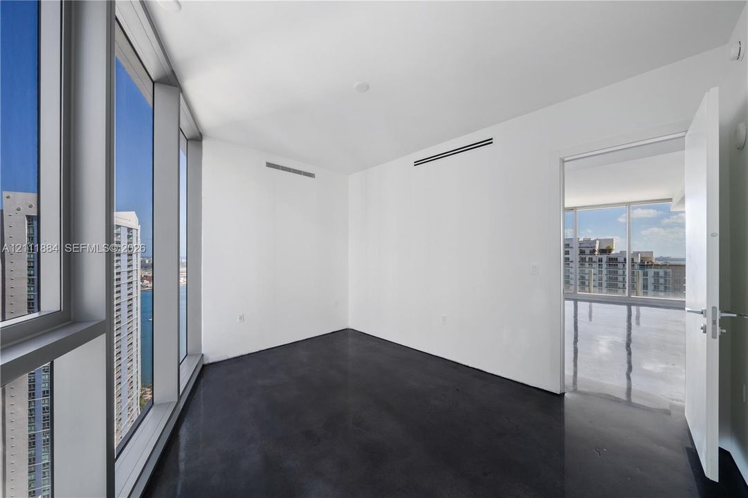 Floor-to-ceiling windows, polished concrete flooring, and high-rise urban scenery