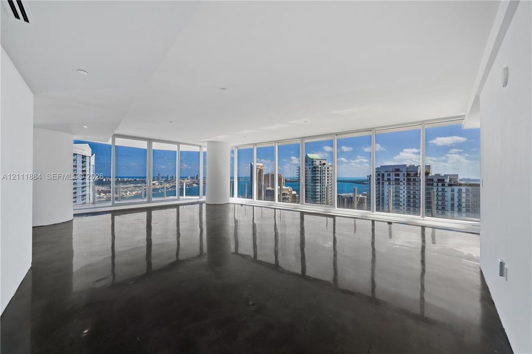 Open-concept interior featuring floor-to-ceiling windows, polished concrete flooring, recessed lighting, and expansive city and water exposure