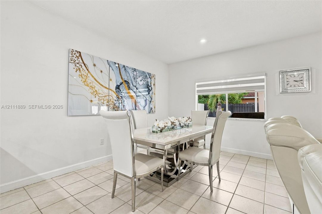Neutral-toned ceramic tile flooring, clean white wall finishes, and a single-pane window featuring horizontal blinds