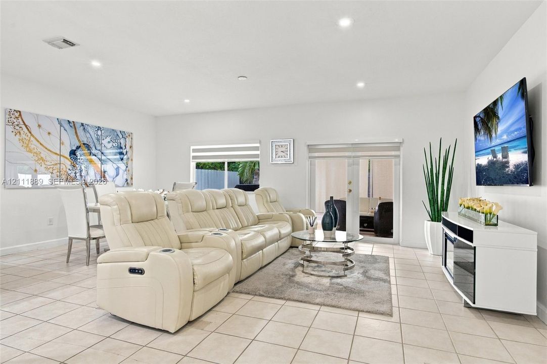 Open concept room featuring large format tile flooring, recessed lighting, and a set of glass-paneled sliding doors