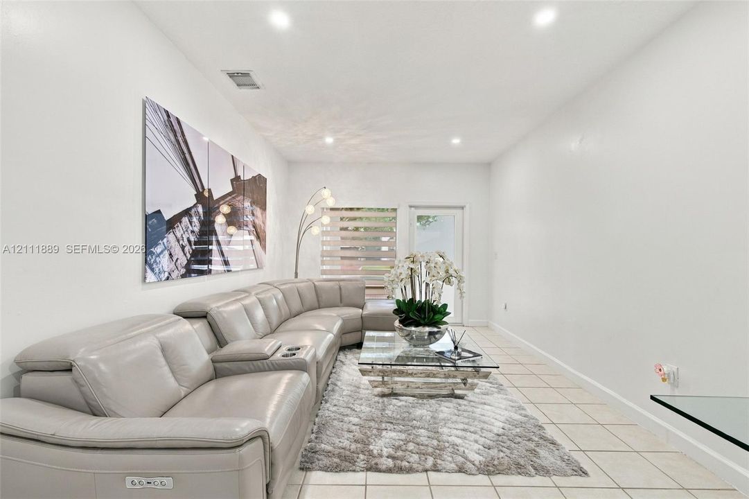 Neutral-toned tile flooring, recessed ceiling lighting, and horizontal window shades