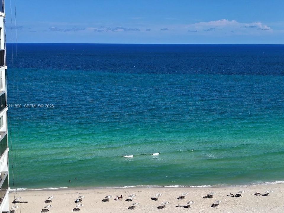 High-rise exterior featuring a direct oceanfront position, sand beach access, and panoramic coastal horizon