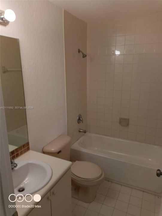 Full bathroom featuring a white vanity with a drop-in basin, tiled shower enclosure, bathtub, and wall-mounted vanity mirror