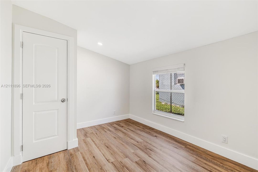 Interior space featuring wood-finish flooring, a recessed ceiling light, a single-pane window, and a white paneled door