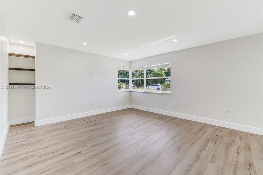 Interior space featuring wood-finish flooring, recessed lighting, corner window configuration, and built-in wall shelving