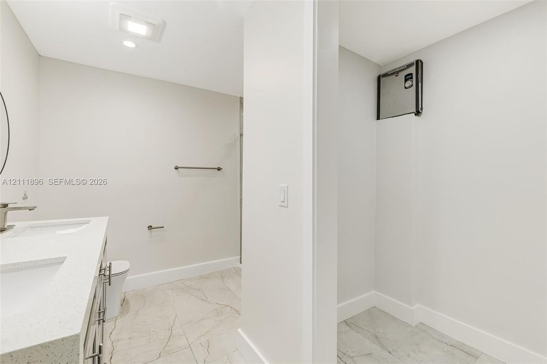 Dual-sink vanity with a quartz countertop, recessed ceiling lighting, and tile flooring featuring a veined pattern