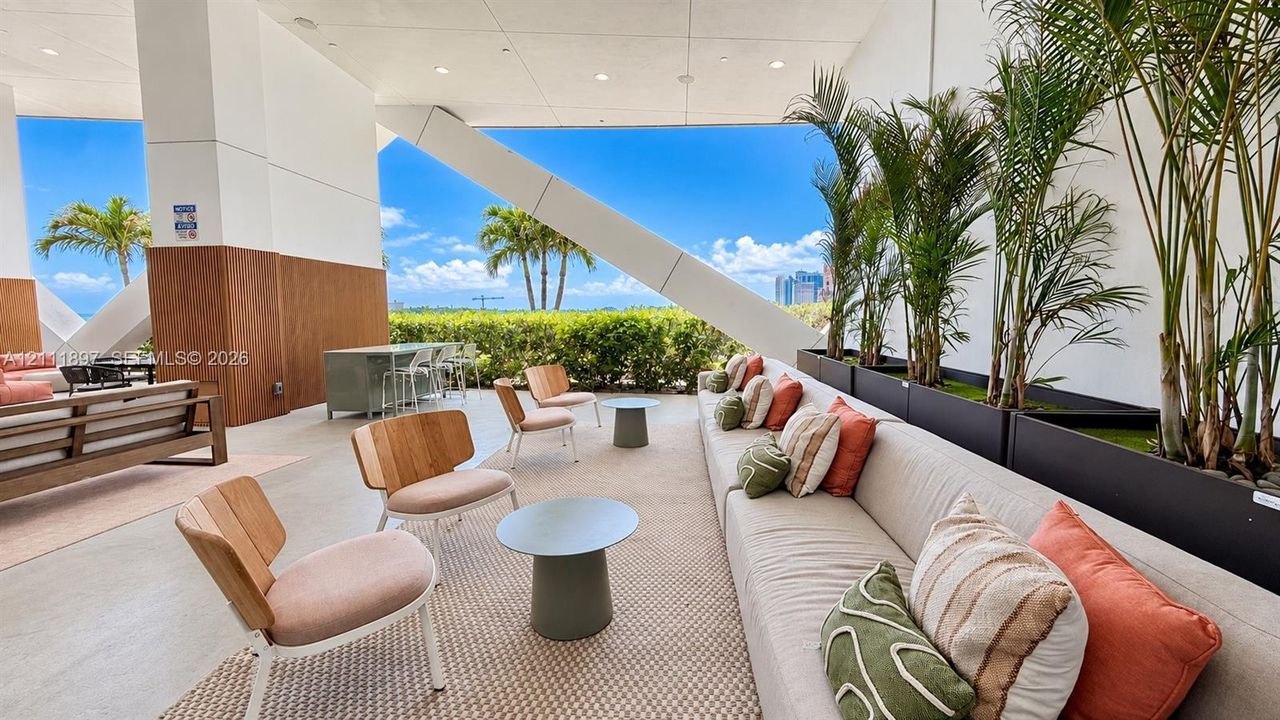 Covered outdoor terrace featuring wood-paneled walls, large-scale structural bracing, integrated plant containers, and a concrete floor finish