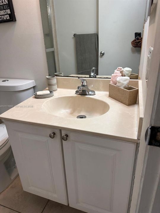 Bathroom vanity featuring white cabinetry, a molded countertop with integrated basin, polished metal faucet, and wall-mounted mirror