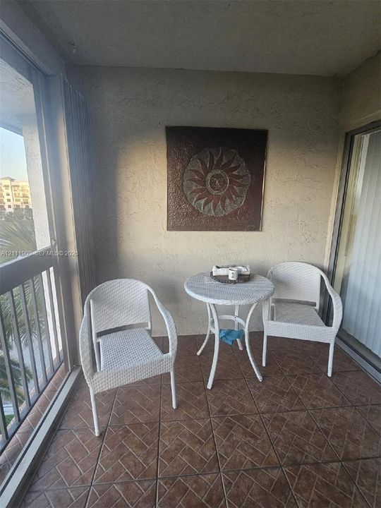 Covered balcony featuring textured walls, metal railing, and ceramic tile flooring