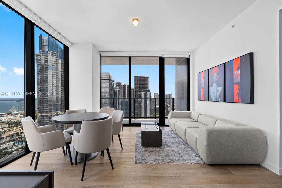 Floor-to-ceiling glass windows, wide-plank wood-finish flooring, and an integrated balcony with metal railing