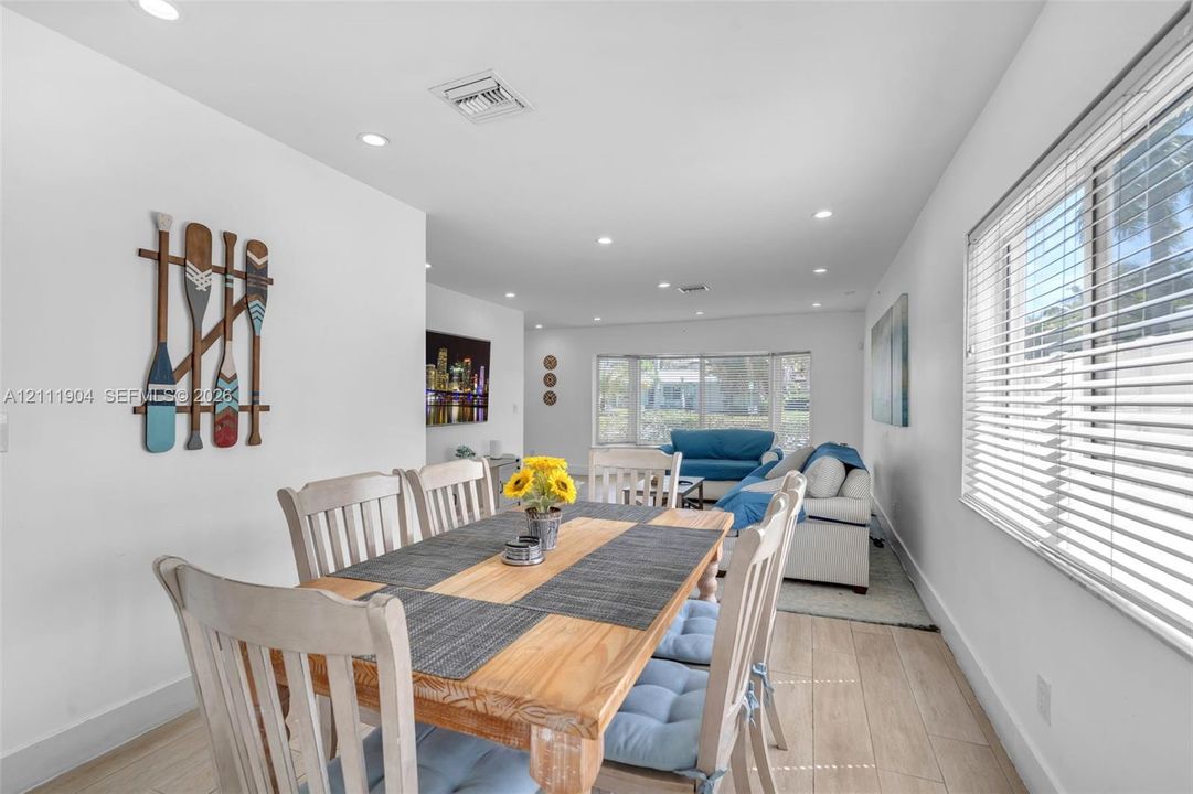 Open-concept living space featuring wood-finish flooring, recessed lighting, and large windows with horizontal blinds