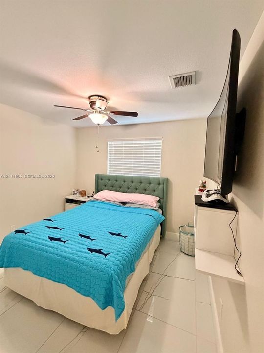 Neutral tile flooring, ceiling fan with light fixture, and horizontal blind window treatment