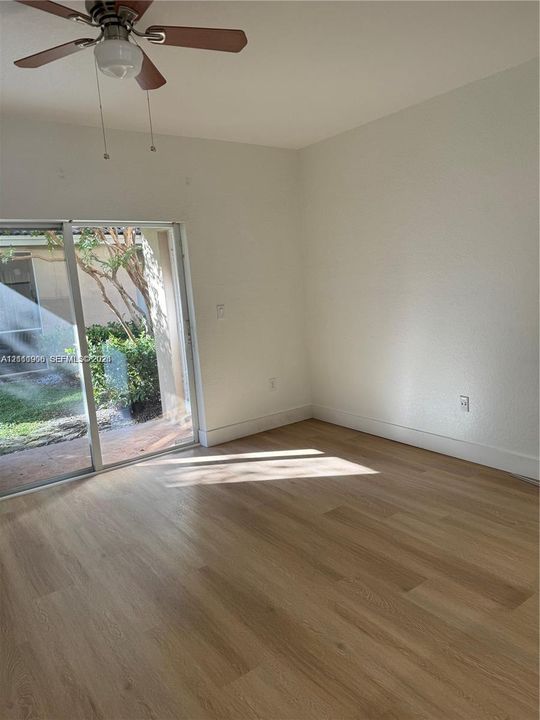 Interior space featuring wood-finish flooring, sliding glass door, and ceiling fan with integrated lighting