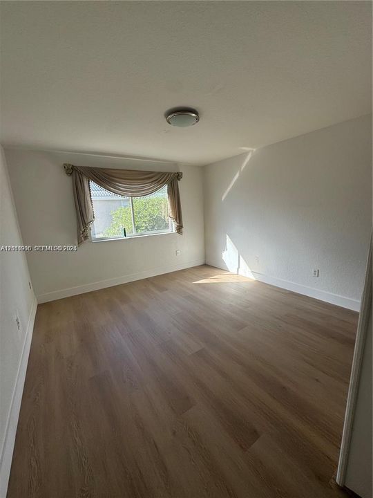 Neutral interior space featuring wood-finish flooring and a flush-mount ceiling light