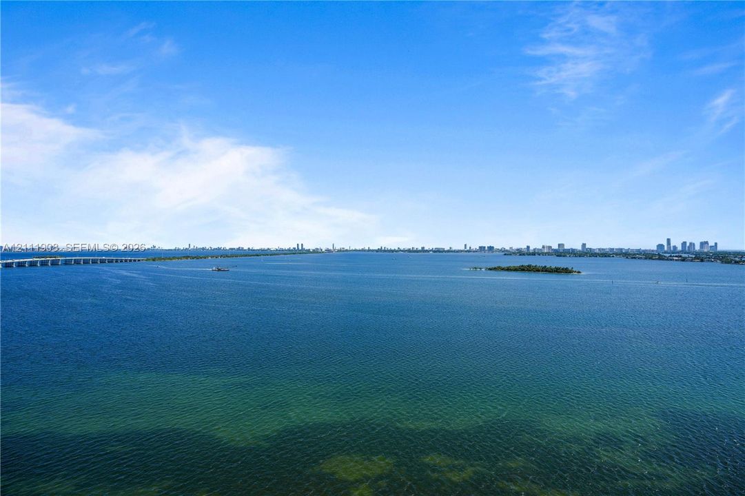 Aerial perspective of expansive open water with a distant city skyline and causeway