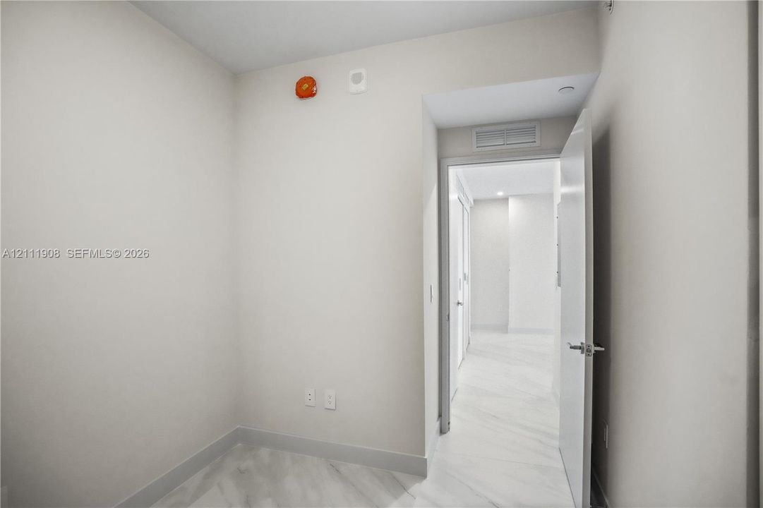 Neutral interior space featuring stone-finish flooring and a white swing door with chrome hardware