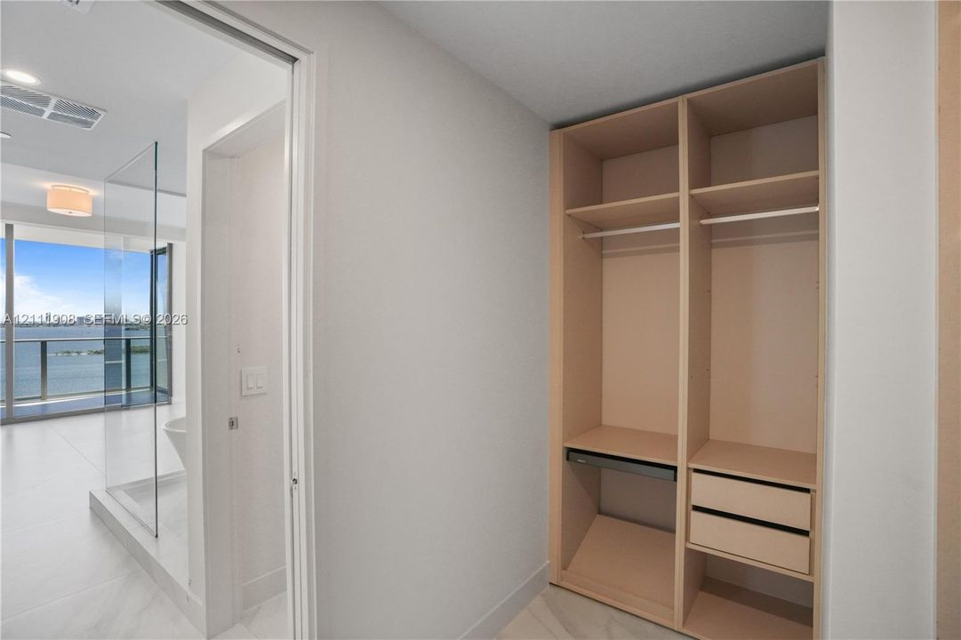 Built-in closet featuring light-toned cabinetry, two storage drawers, and hanging rods