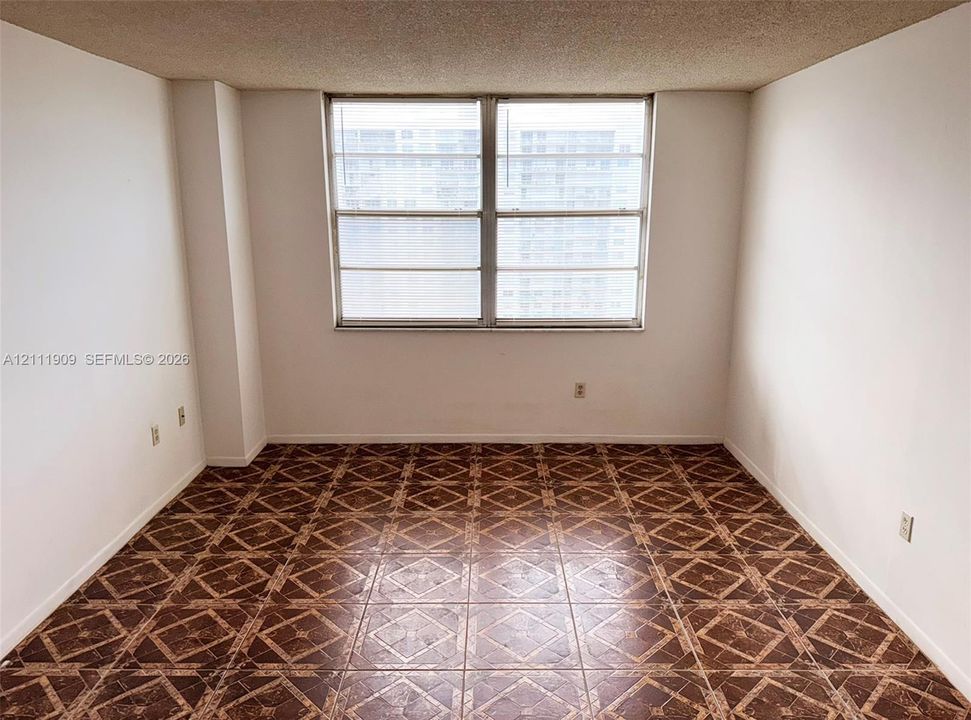 Interior space featuring patterned tile flooring, textured ceiling, and a large dual-pane window