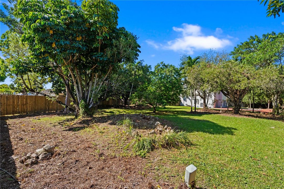 Expansive lot featuring mature trees, manicured lawn areas, and perimeter wood fencing