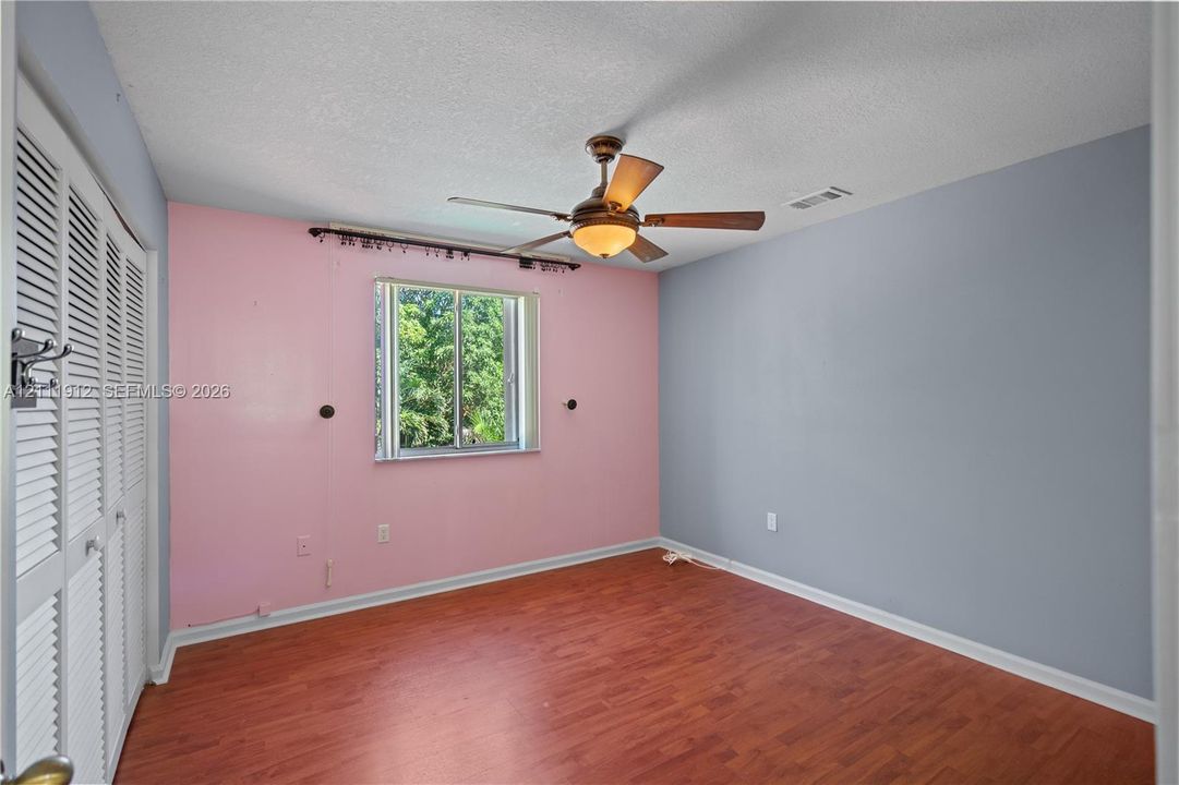 Wood-finish flooring, ceiling fan with integrated lighting, and louvered-style closet doors