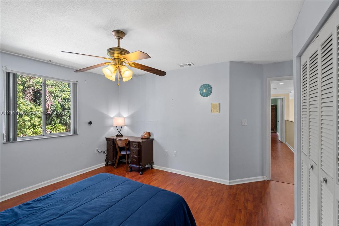 Room with wood-finish flooring, ceiling fan with integrated lighting, dual-pane window, and louvered bi-fold closet doors