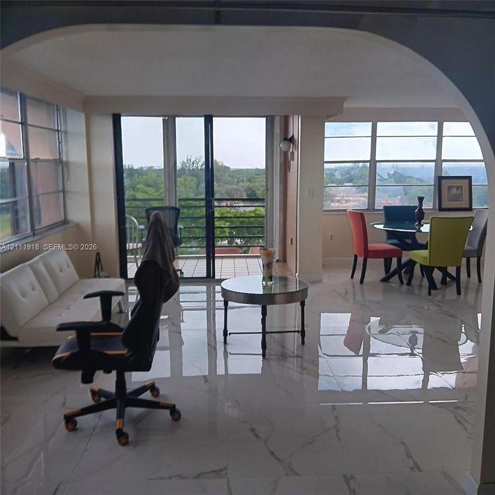 Polished stone-finish flooring with veining detail, arched architectural entryway, floor-to-ceiling windows, and private balcony access