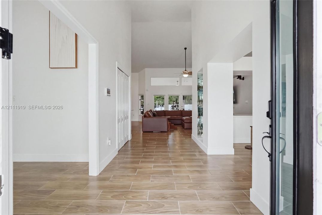 Entryway featuring wood-finish tile flooring, vaulted ceilings, and a framed glass-panel entry door