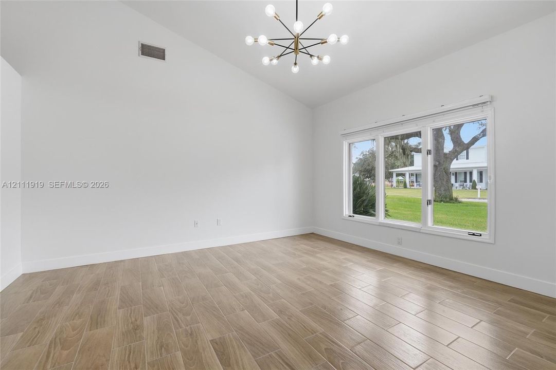 Vaulted ceilings, wood-finish tile flooring, and a multi-light modern chandelier