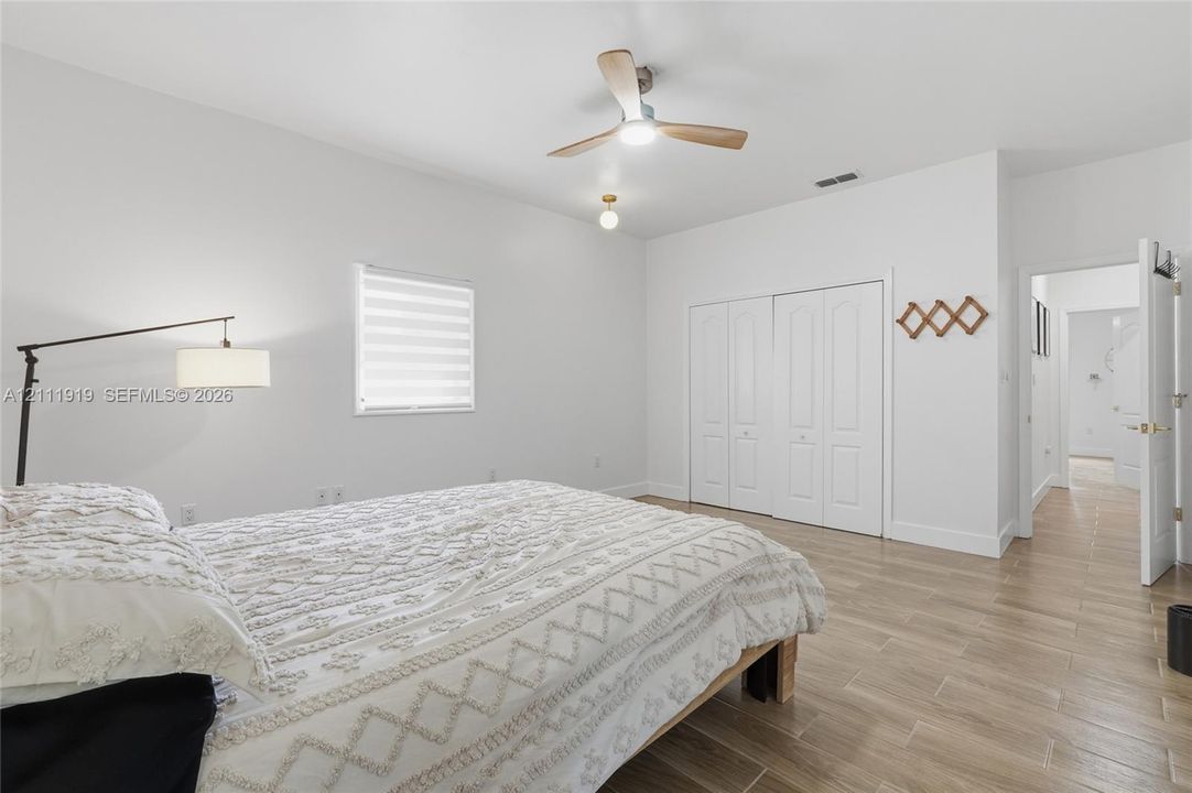 Wood-finish flooring, ceiling fan with integrated light, dual-pane window with adjustable shade, and double-door closet cabinetry
